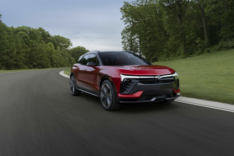 Passenger’s side view of the 2024 Blazer EV SS in Radiant Red Tintcoat driving on a road with trees. Preproduction model shown. Actual production model may vary. 2024 Chevrolet Blazer EV available Spring 2023.
