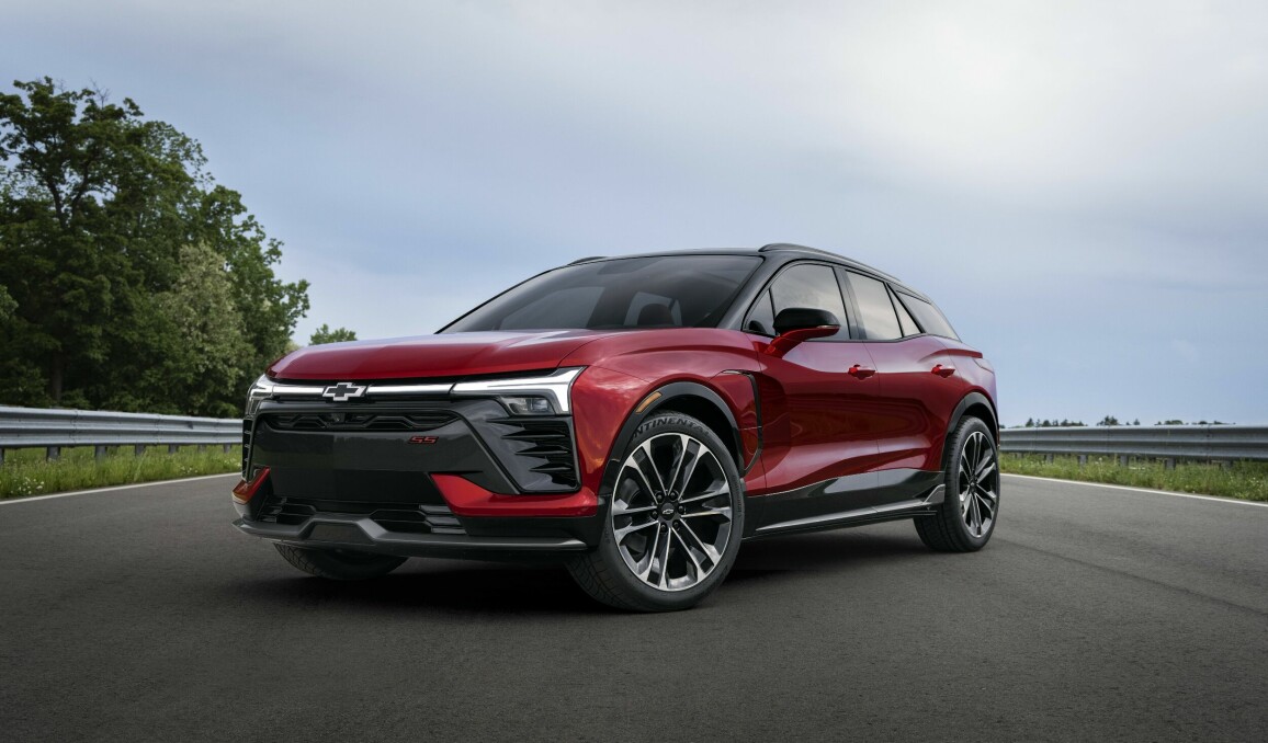Three-quarter view of 2024 Chevrolet Blazer EV SS in Radient Red Tintcoat on a road with trees. Preproduction model shown. Actual production model may vary. 2024 Chevrolet Blazer EV available Spring 2023.